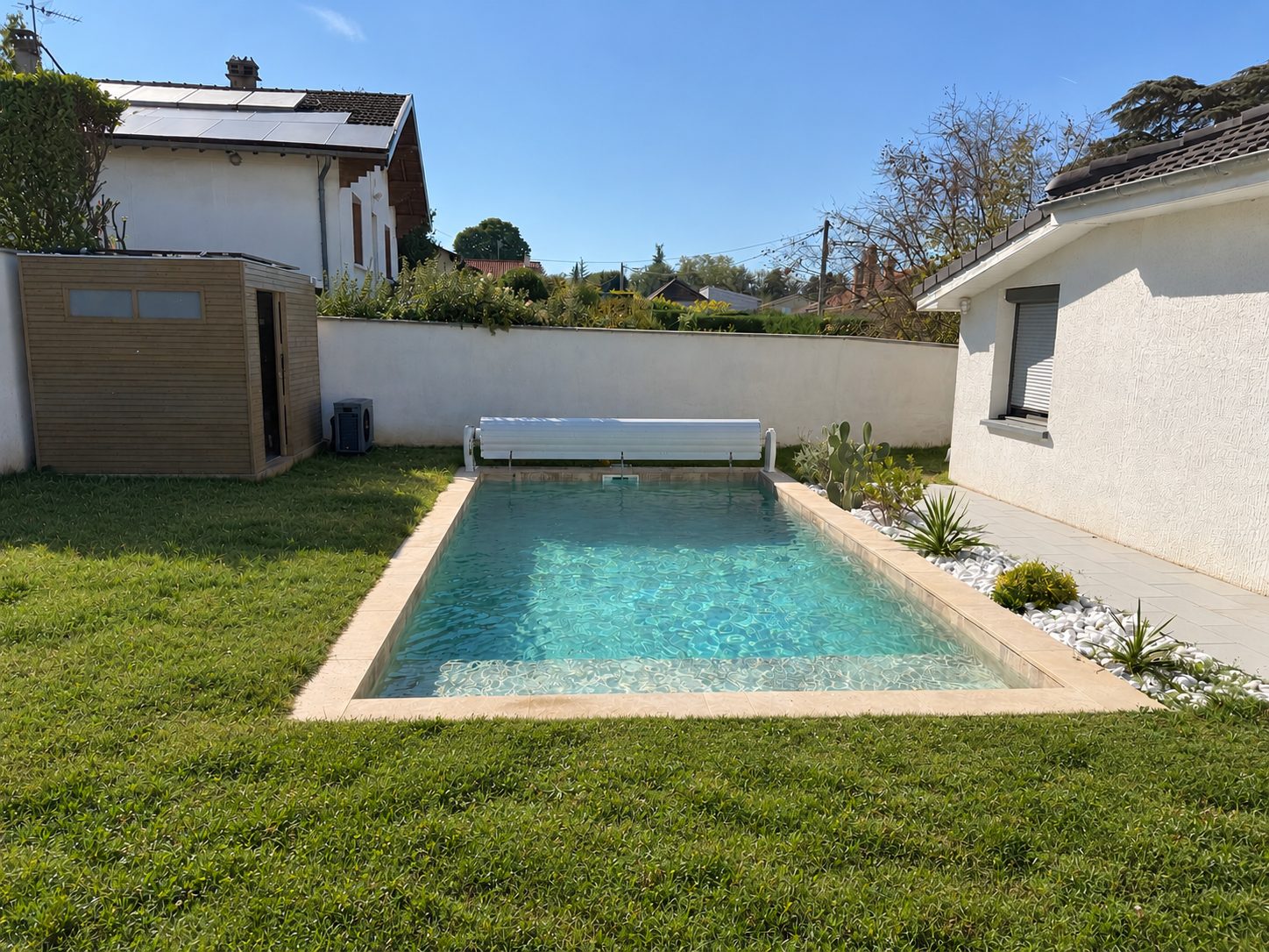 Piscine terminée à Jonage, margelles claires, volet roulant et jardin engazonné