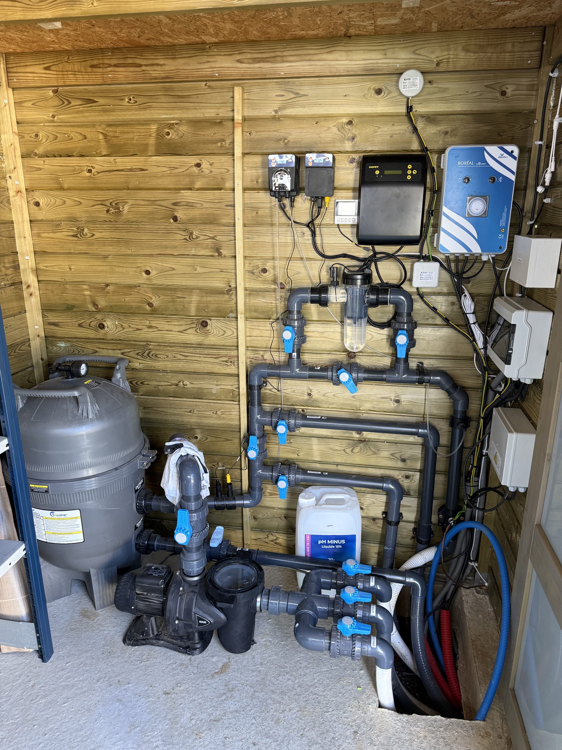Local technique de piscine dans un abri en bois : filtre, pompe et coffret électrique