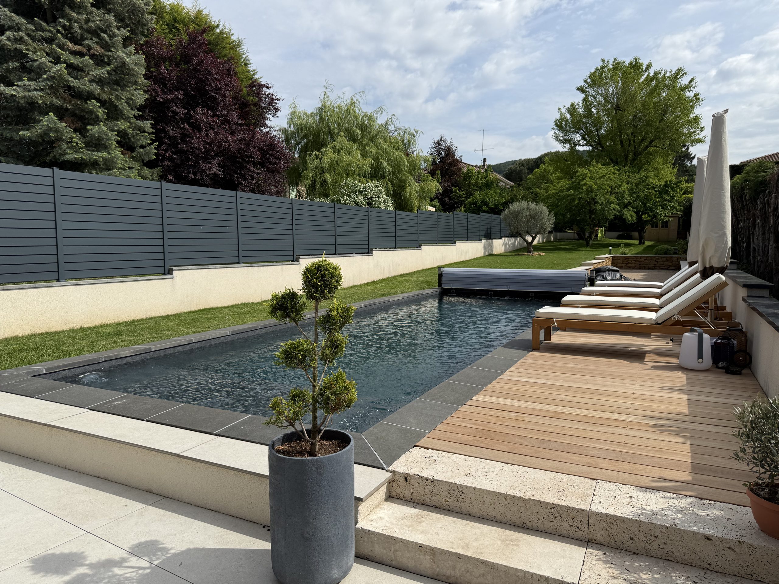Piscine rénovée par Les Bassins de Jules, revêtement gris anthracite et terrasse en bois