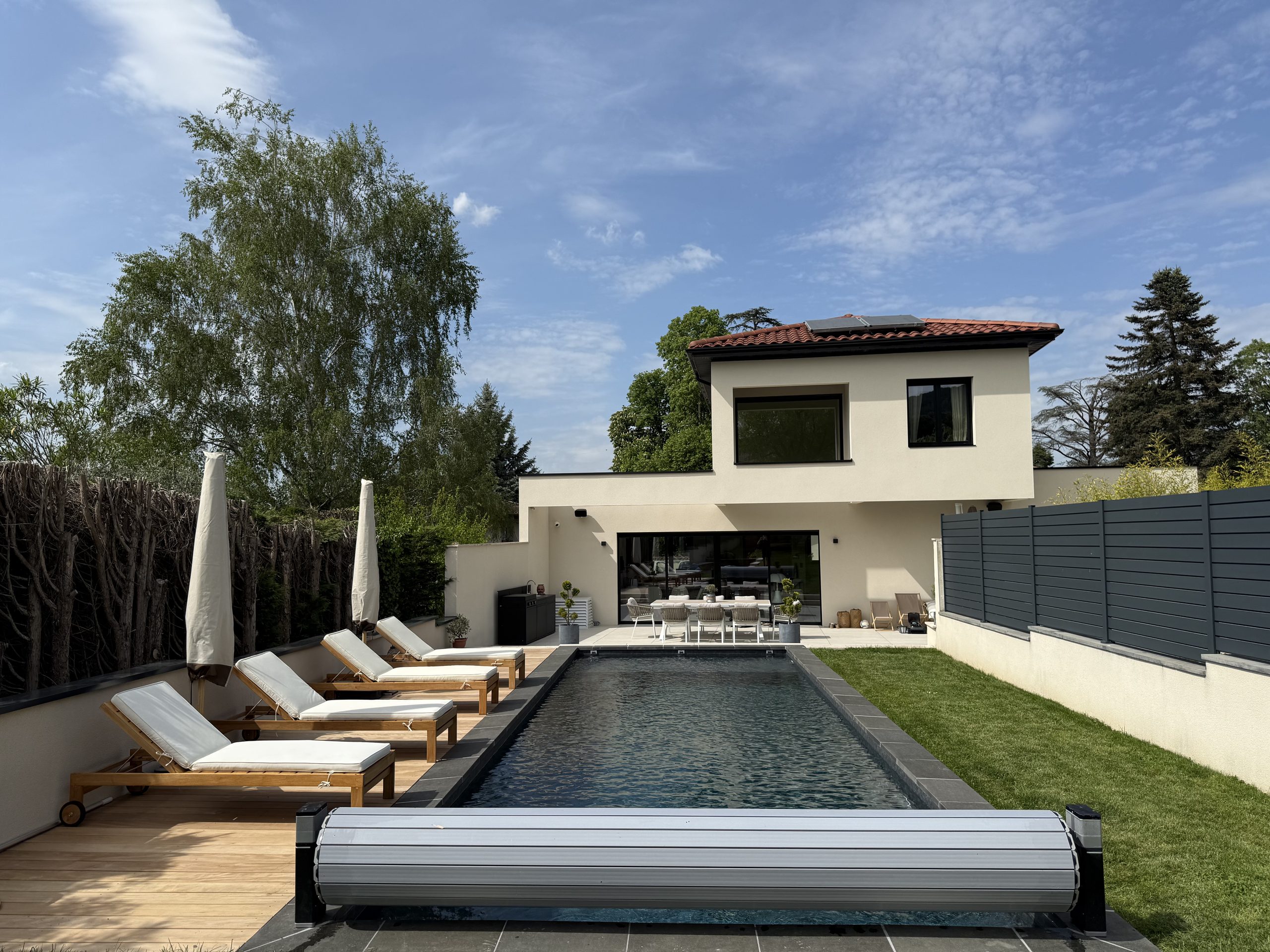 Piscine rénovée devant une maison contemporaine, équipée d'un volet roulant hors-sol