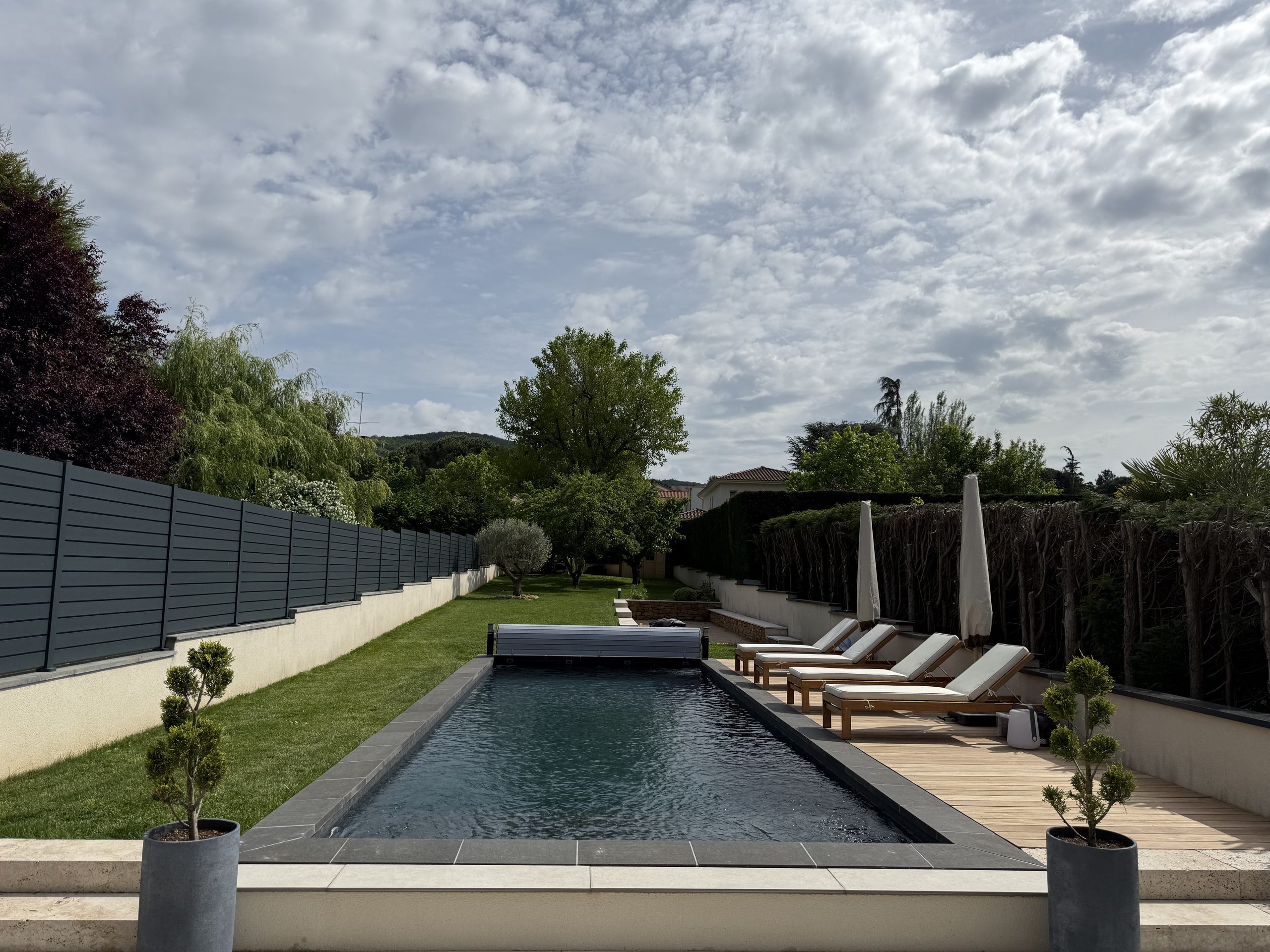 Piscine après rénovation dans son jardin, avec volet roulant et bains de soleil