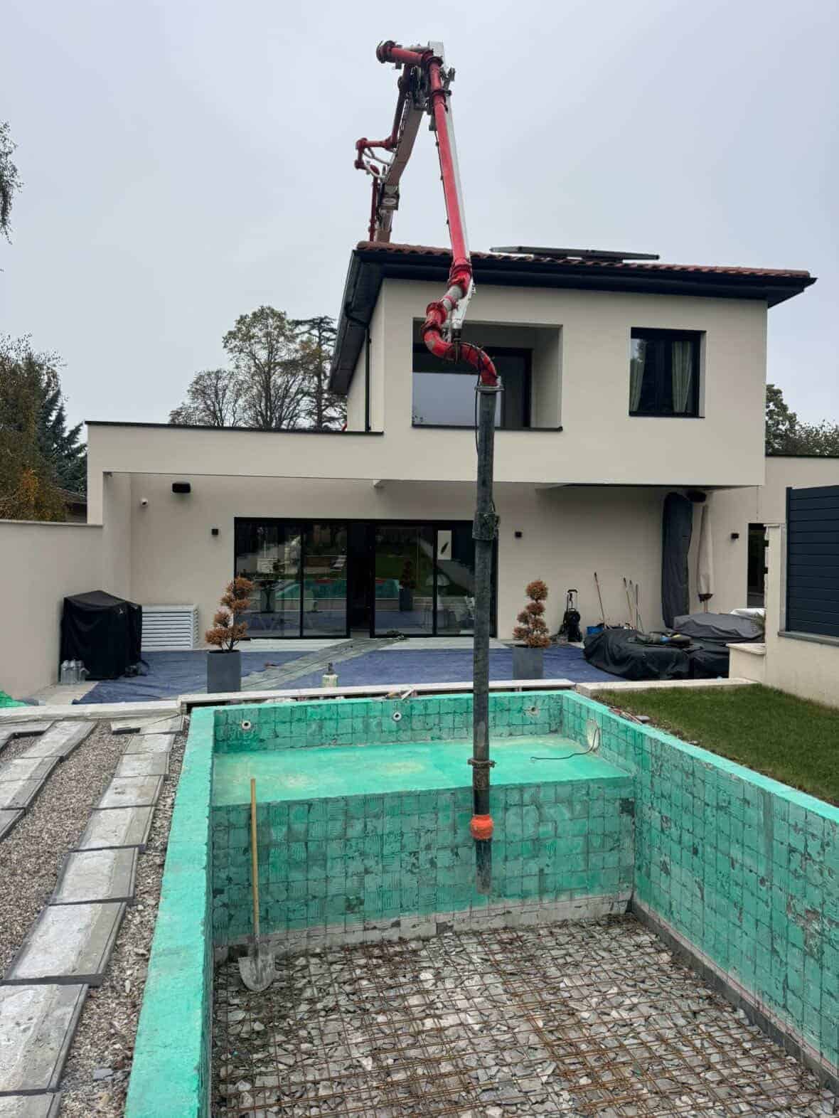 Chantier de rénovation de piscine, bassin mis à nu et grue en action